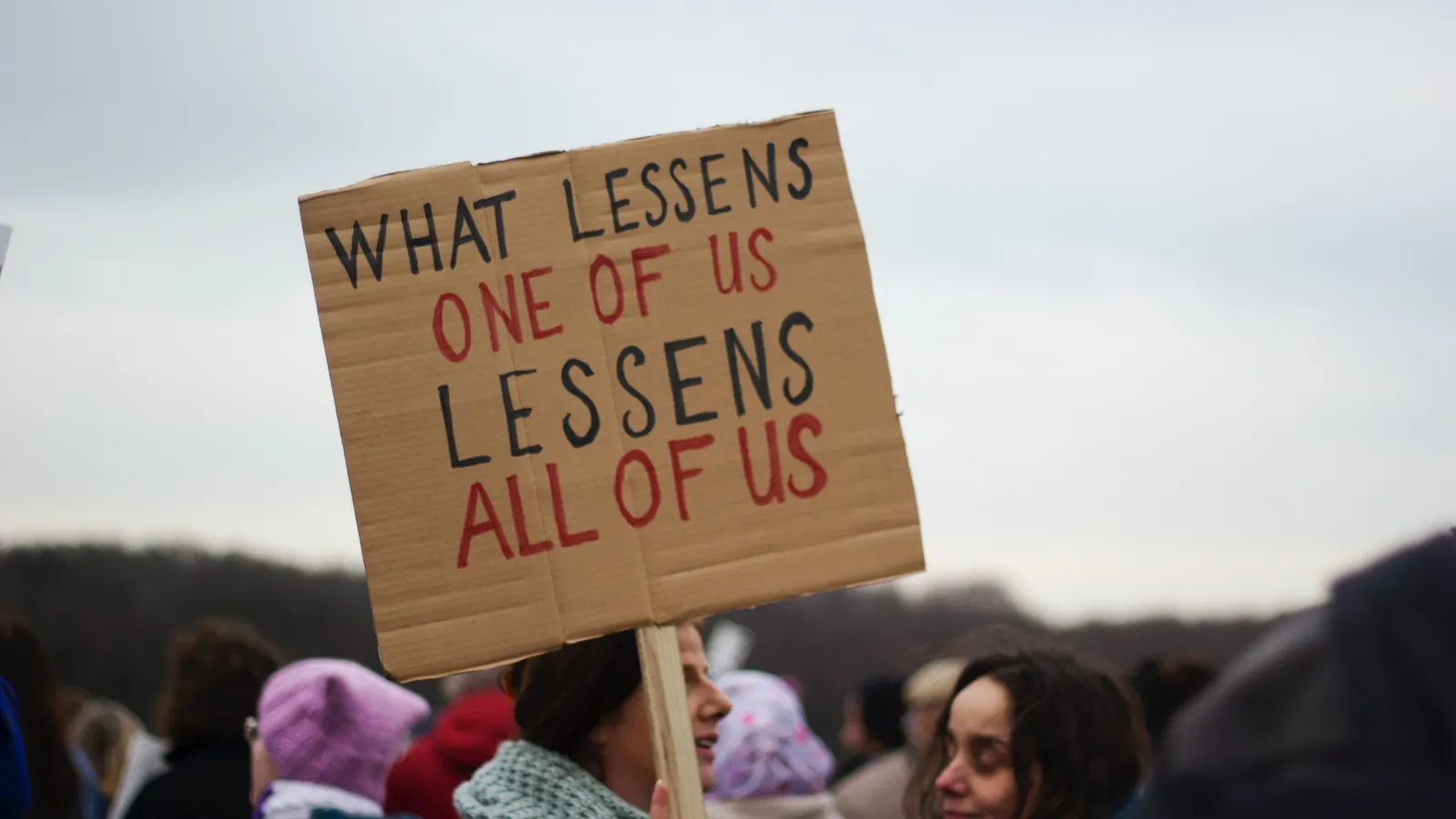 Protest sign that says "What lessens one of us lessens all of us"