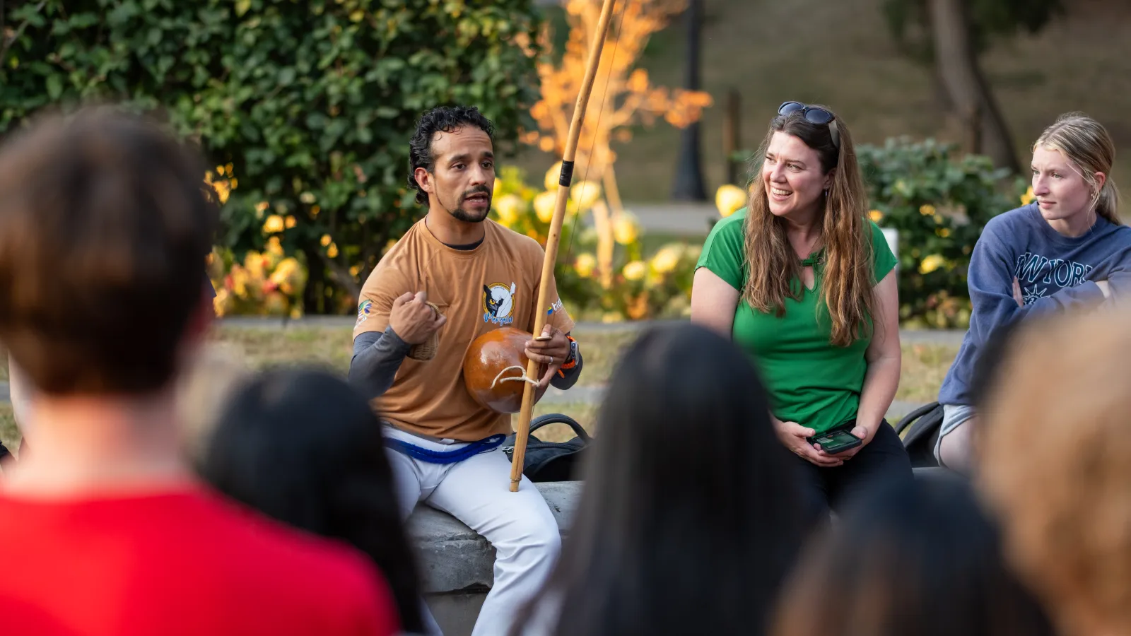 Julio Beltran playing capoeira music on the berimbau and International Affairs Scholars Program Manager Jill Klimpel