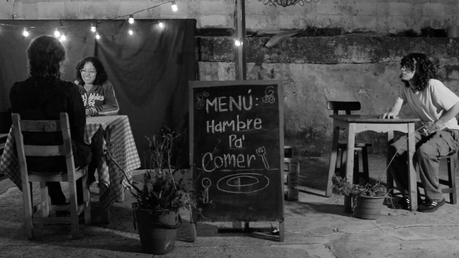scene of film, restaurant; two people at one table in one corner, guy at another table in the other corner