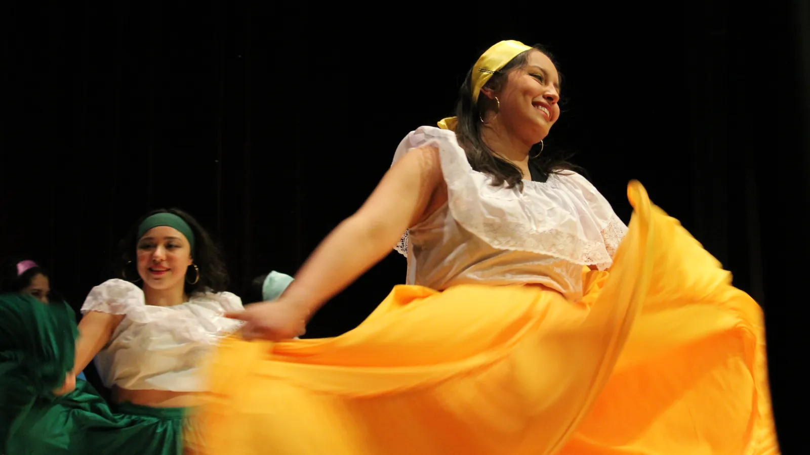woman wearing a yellow skirt and white top dancing