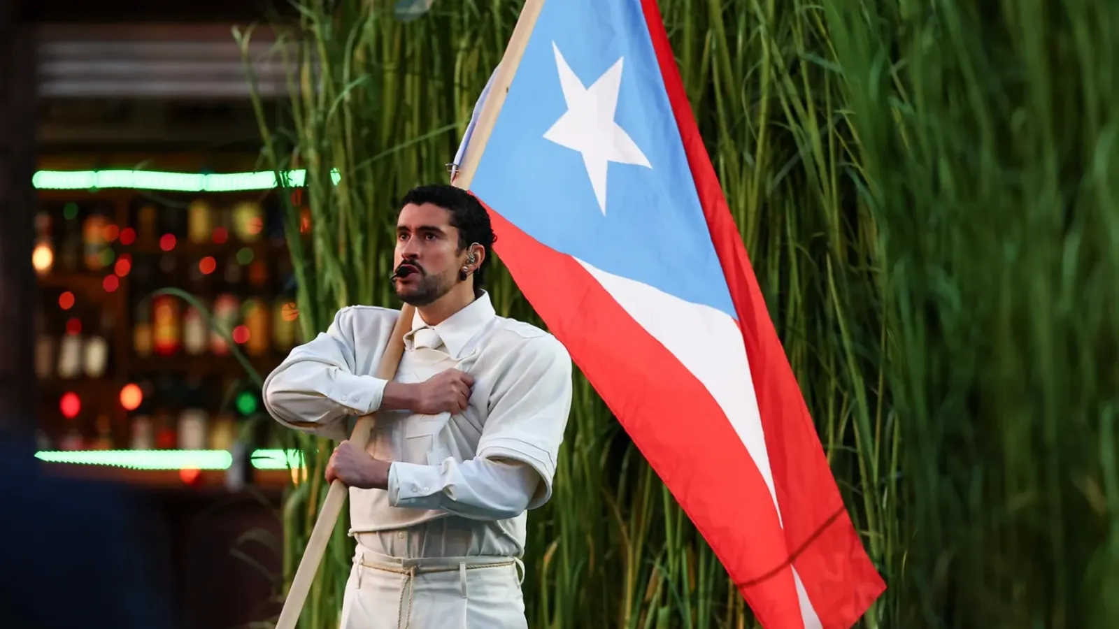 bad bunny in white carrying Puerto Rican flag