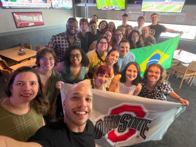 group of people posing for a selfie holding Ohio State flag and Brazil flag