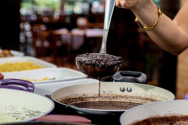 arm of woman holding spoon full of feijoada