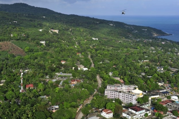 A seaside town on a hill in Haiti. A helicopter flies overhead