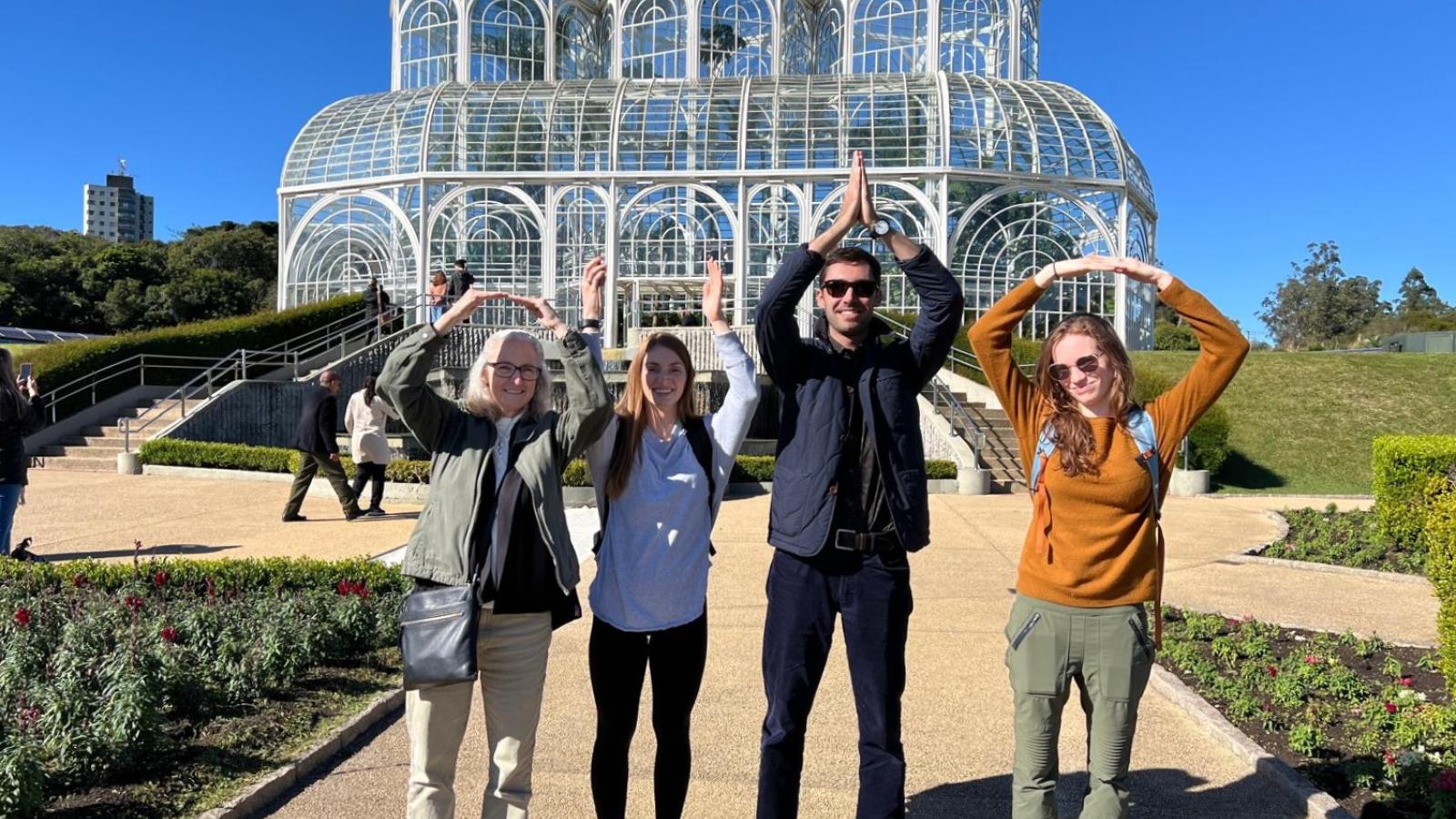 Four IPAST participants spelling out "OHIO" with arms in front of botanical garden